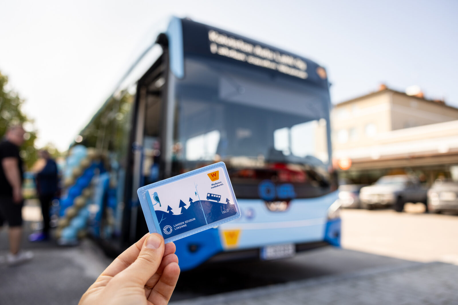 Käsi pitelee matkakorttia. Tausalla LSL:n bussi
